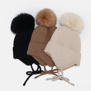 Bonnet en tricot avec cache-oreilles, pompons en fourrure et lanières en noir, café et beige