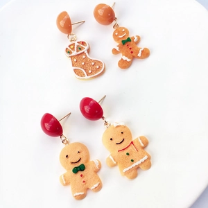 Detailed macro view of handmade gingerbread man and Christmas sock resin stud earrings