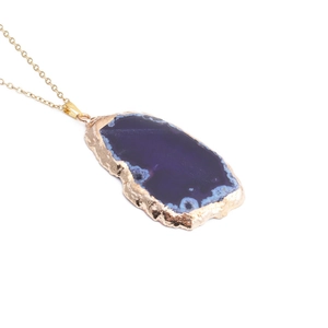Détail du pendentif en tranche d'agate bleu foncé avec bordure dorée et chaîne fine
