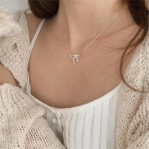 Close-up of polished 925 sterling silver bow pendant necklace on a model neck