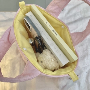 Top view of pink quilted tote bag interior with yellow lining showing daily essentials