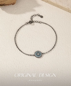 Macro detail of S925 silver black gunmetal chain bracelet with evil eye turquoise pendant