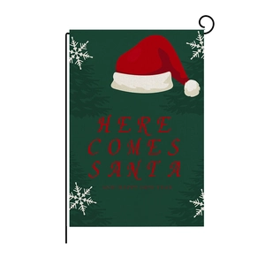 Close-up of linen garden flag with Here Comes Santa text and festive holiday graphics