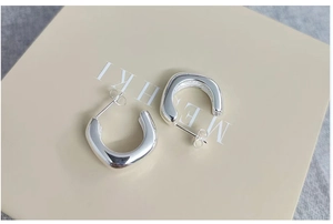Détail macro de boucles d'oreilles carrées en argent avec finition miroir poli