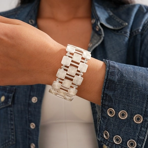Macro view of silver wide cuff bracelet featuring textured square patterns and spiral design