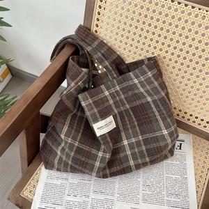 Detail of vintage plaid wool tote bag with brand label on a retro wicker chair