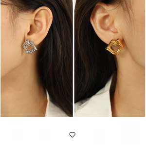 Close-up of polished 18k gold and silver lip-shaped stud earrings worn by a model