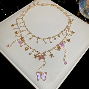 Macro detail of double-layer necklace with gold butterfly charms and purple resin wings