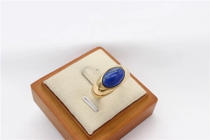 Detailed shot of a gold titanium ring with an oval blue gemstone on a display stand