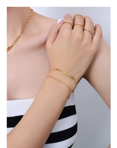 Nahaufnahme der goldenen mehrlagigen Titan-Armbänder und Ringe mit poliertem Finish