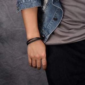 Detail of layered black leather bracelet with braided strands on a man's wrist