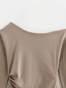 Close-up of the asymmetric neck and side ruching detail on the taupe knit top