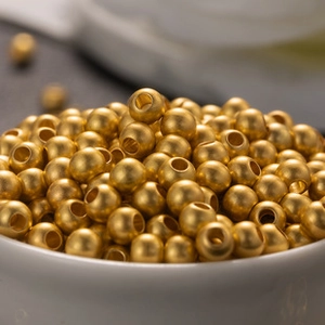 Macro shot of small golden spherical beads for DIY jewelry and handicraft making