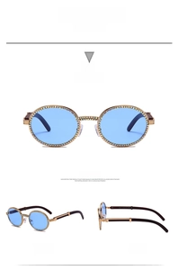 Detail view of oval crystal-studded sunglasses with gold metal frame and blue lenses