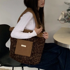 Leopard print plush tote bag with solid outer pocket and metal logo worn by a model