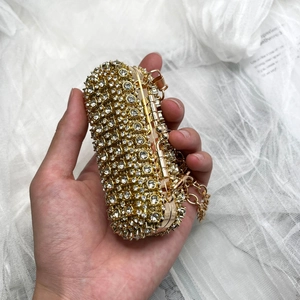 Detailed macro view of a gold lipstick-shaped evening clutch bag with sparkling rhinestones