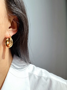 Nahaufnahme eleganter goldener Doppel-Creolen an einem weiblichen Modellprofil
