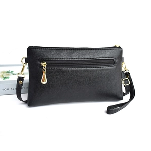 Detail of black lychee grain leather crossbody bag with gold zippers and hardware