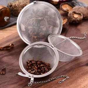 Detail of stainless steel tea strainers with seasoning on a wooden cutting board