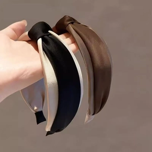 Detail view of two knot-design satin headbands in bicolour black, beige and brown