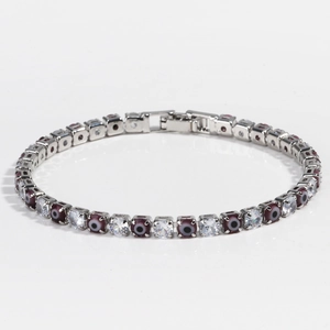 Detail view of silver tennis bracelet with cubic zirconia and purple evil eye charms