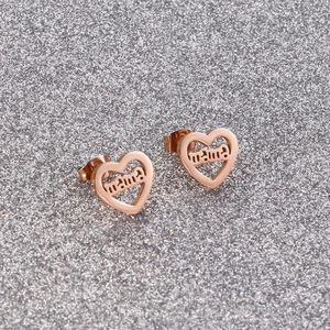 Detail of rose gold heart earrings featuring cut-out mama letters on sparkly background