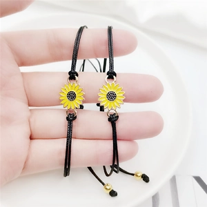 Detail of friendship bracelets with sunflower charms and adjustable black woven cords