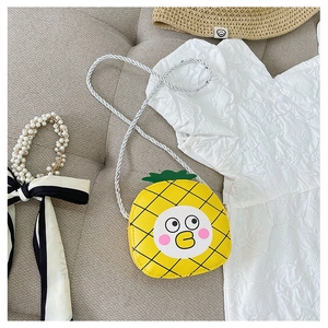 Detail of cute yellow pineapple crossbody bag with cartoon face and green leaf decoration