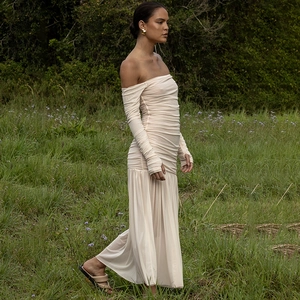 Détail d'une robe longue élégante à épaules dénudées en beige avec manches longues et plis