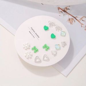7-day set of small silver and green stud earrings with bows and hearts on a display card