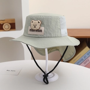 Detail view of mint green sun hat with mesh panels, neck flap, and cute bear patch