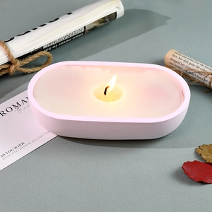 Top view of a pink oval candle jar burning on a retro desk with autumn leaves decoration
