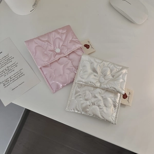Close-up of pink and beige heart quilted satin pouch with button and woven label