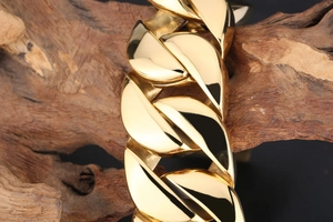 Macro detail of high-quality gold plated Cuban link chain on a rustic wood background