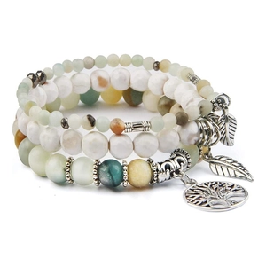 Macro detail of multi-layered beaded bracelet with tree of life and leaf charms