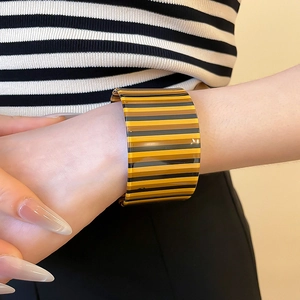 Close-up of a wide striped acrylic cuff bracelet with vibrant amber and black patterns