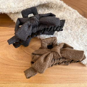 Detail of soft fabric wrapped bow hair claws in charcoal grey and warm brown colors