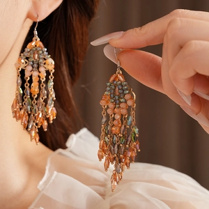 Vintage bohemian tassel earrings featuring orange and green beads on a gold ear hook