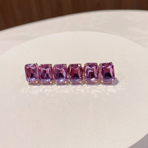 Macro shot of pink rectangular rhinestones set in a golden metal hair clip base