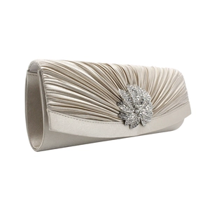 Detail of champagne satin evening clutch with pleated fabric and floral rhinestone ornament