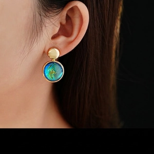 Fashionable round resin stud earrings with blue-green gradient on model for jewelry display