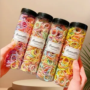 Close-up of four jars containing assorted colorful elastic hair bands with handmade labels