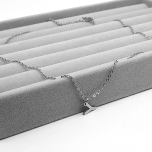 Silver stainless steel necklace with letter T pendant on grey velvet display tray