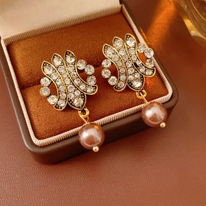 Macro shot of gold-tone hollow earrings with sparkling rhinestones and brown pearl pendants