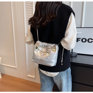 Detail view of silver quilted bucket bag with metallic leather and heart charm on chain
