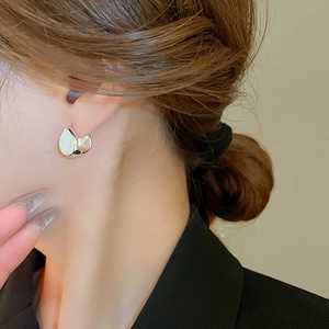 Silver U-shaped drop earrings with white cat eye stone shown on a female model
