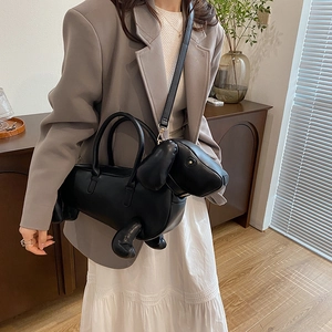 Creative dachshund-shaped black leather handbag and shoulder bag worn by a model