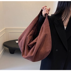 Close-up of large brown suede tote bag showing soft matte texture and wide shoulder strap