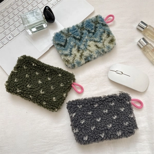 Flat lay of colorful plush storage bags with zippers and pink loops on a soft white cloth