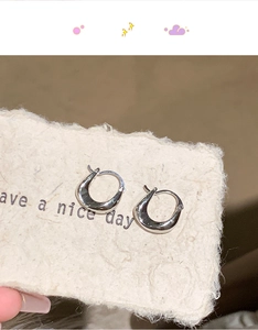 Macro detail of silver U-shaped earrings with a minimalist mirror polished finish